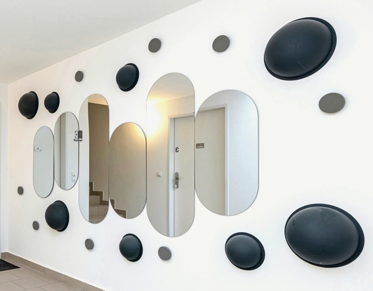 Installation „Between me and myself“: ovale Spiegel zwischen dunklen Halbkugeln und grauen Scheiben an der Wand
